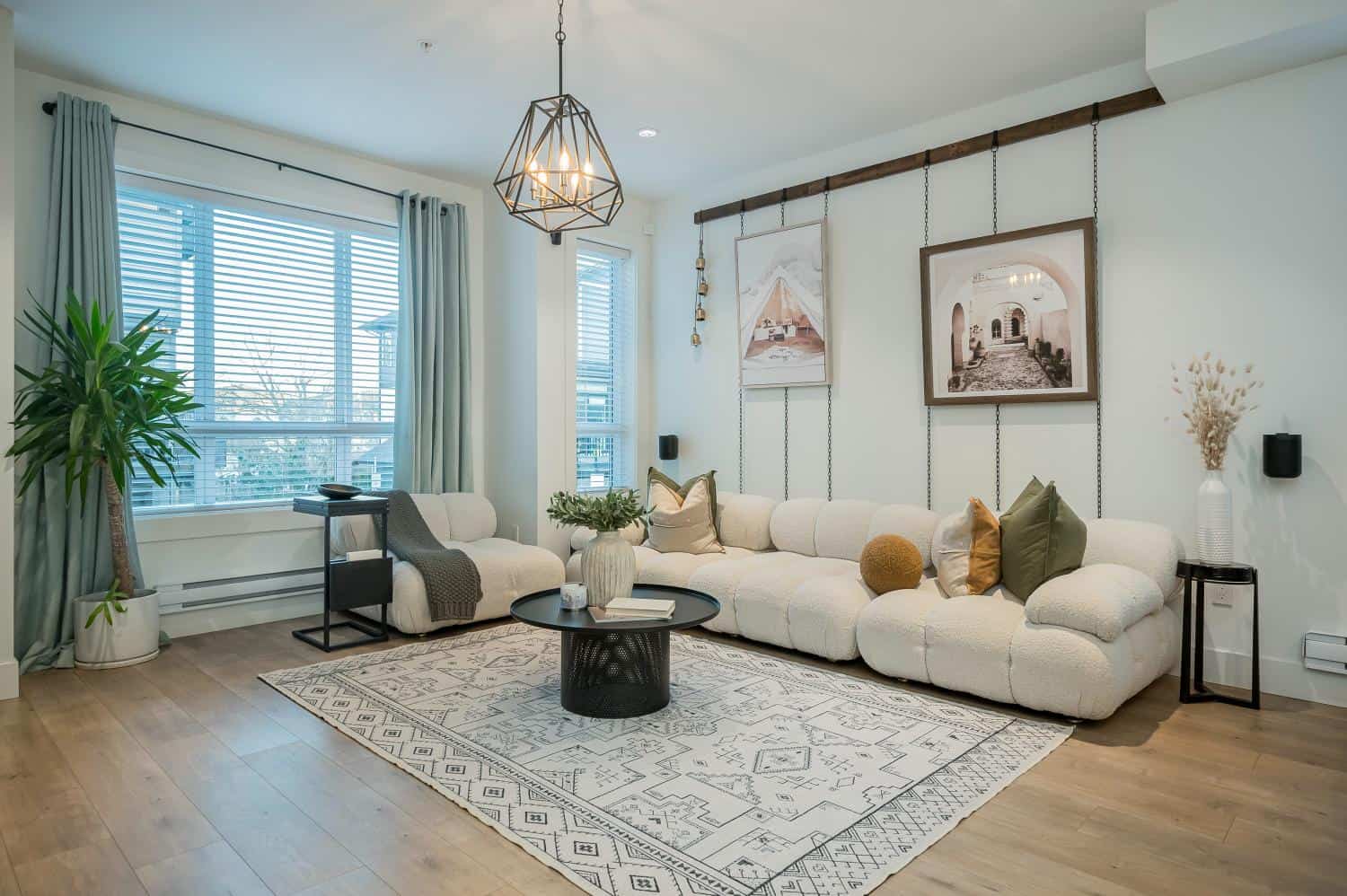 Modern living room with large windows, neutral-toned furniture, and stylish wall art, showcasing cozy, contemporary decor and natural light, ideal for homebuyers interested in Vancouver real estate.