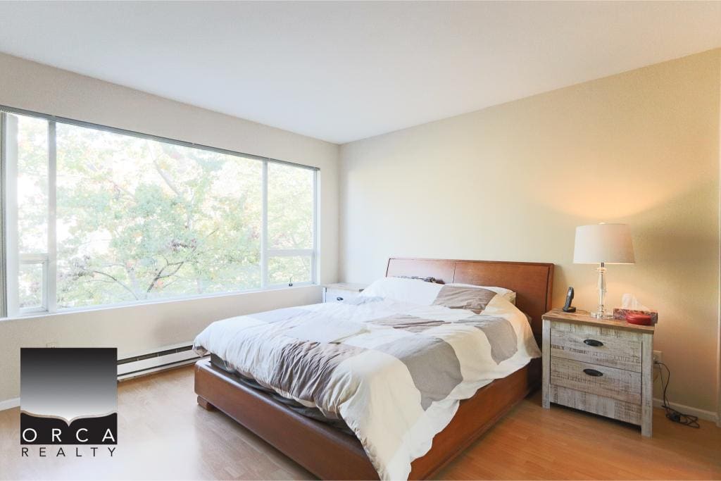 Bright master bedroom with large windows offering natural light and a view of trees, modern furniture, and stylish decor. Perfect for Vancouver real estate buyers seeking comfortable, contemporary homes.