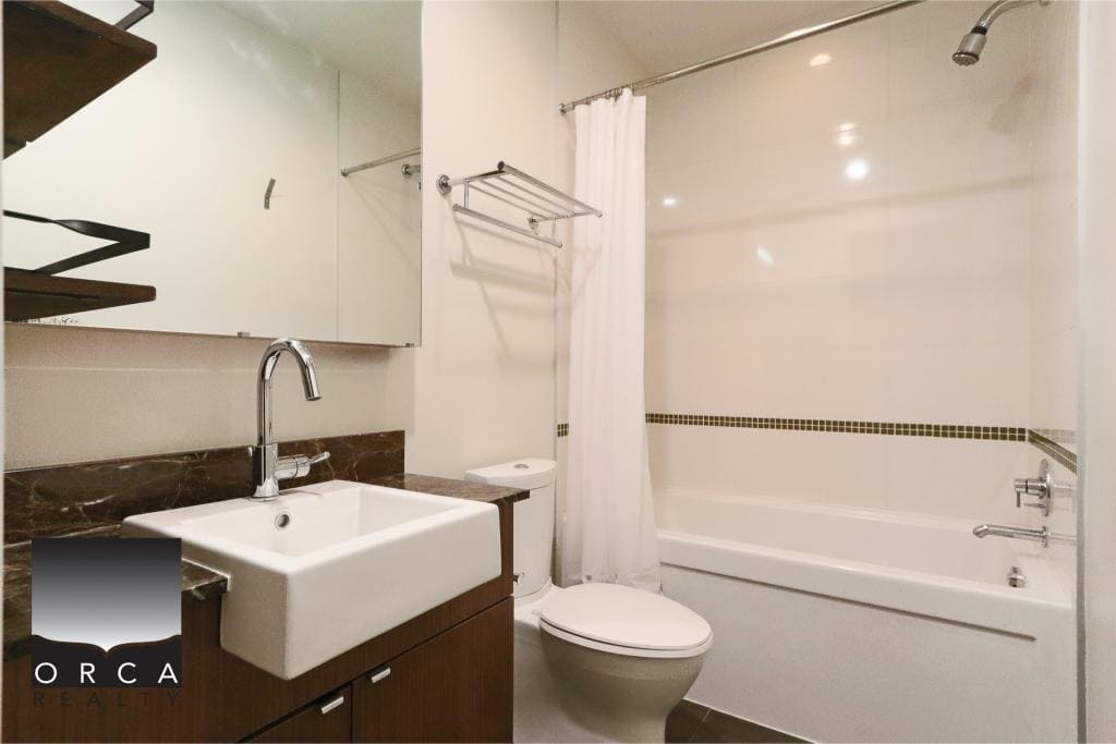 Modern bathroom with bathtub, shower, and white fixtures, featuring a sleek vanity with a large mirror, ideal for Vancouver real estate listings and property showings.