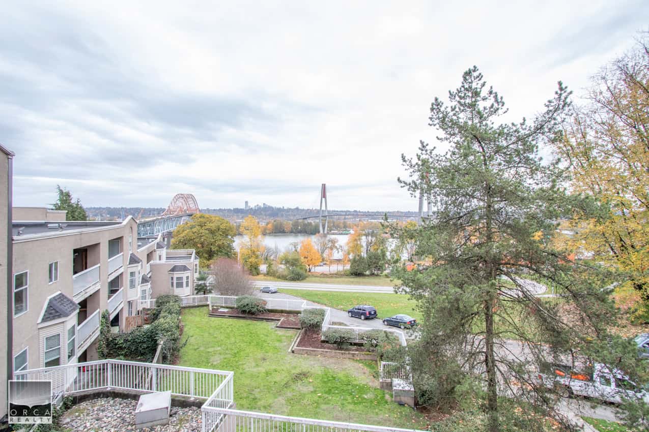 Vancouver waterfront view with residential buildings, trees, a bridge, and cityscape in background, showcasing desirable property location near water and nature.