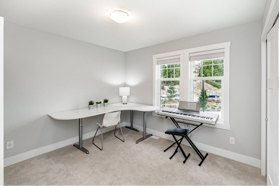 Sunny home office with large windows, modern decor, and a digital piano for versatile living space in Orca Realty Inc. property.