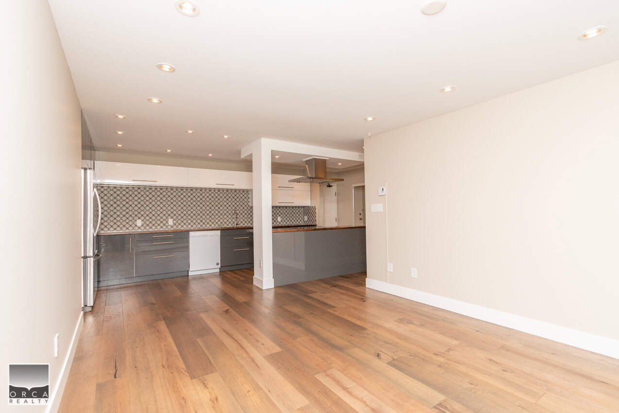 Modern open-concept kitchen with sleek grey cabinetry and hardwood flooring, ideal for Vancouver Island real estate buyers.