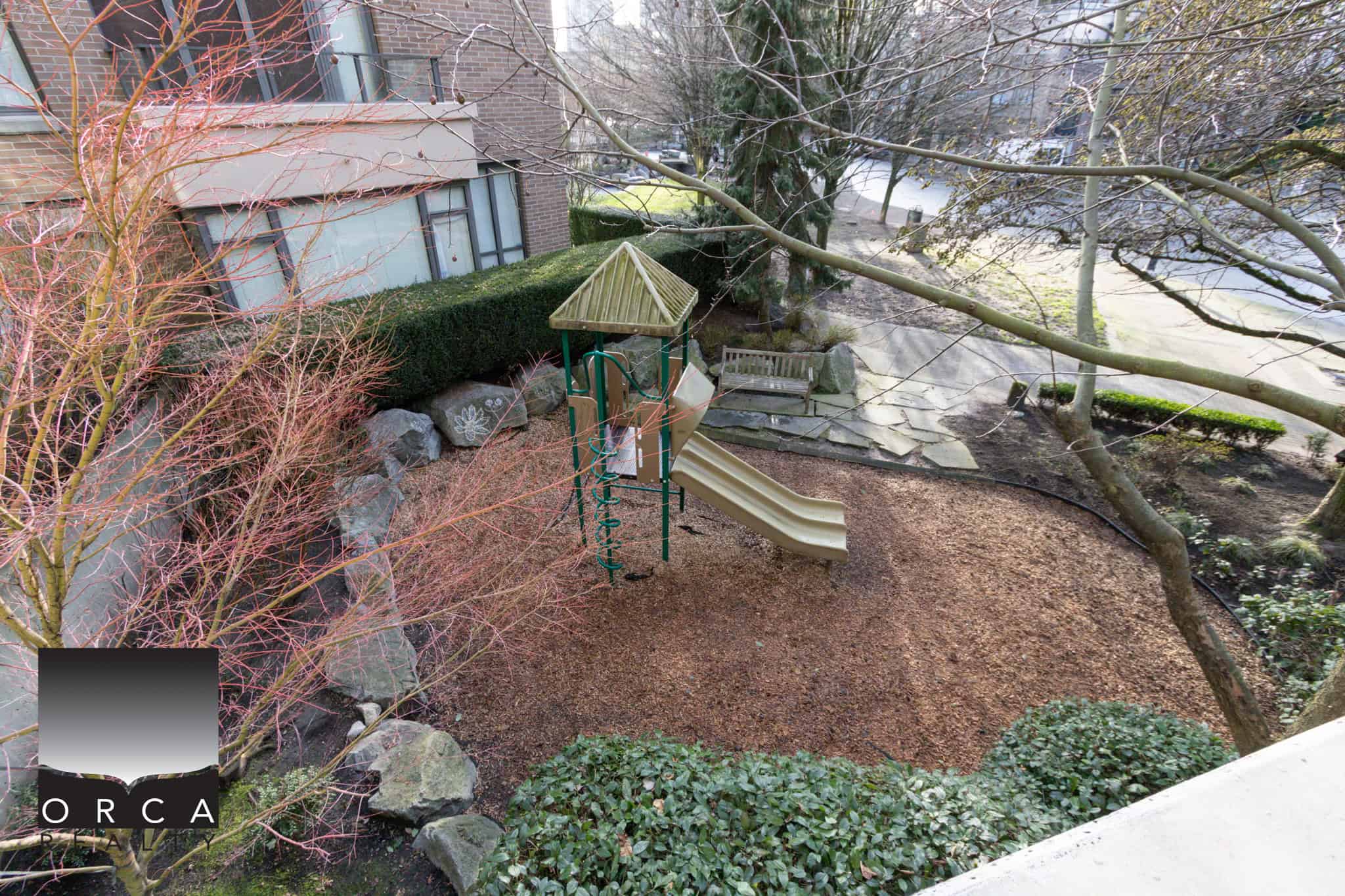 Bright and inviting playground area with slide and climbing structure in a North Vancouver residential yard. Perfect for family fun and outdoor activities.