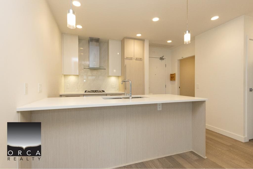 Bright modern kitchen with white cabinetry, stainless steel appliances, and an island, offered by Orca Realty Inc., located in a desirable area of Ontario.