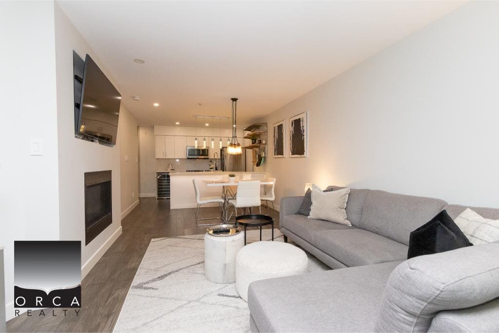 Bright modern living room with grey sofa, cozy decor, open-concept kitchen and dining area, ideal for Vancouver rentals or real estate listings.