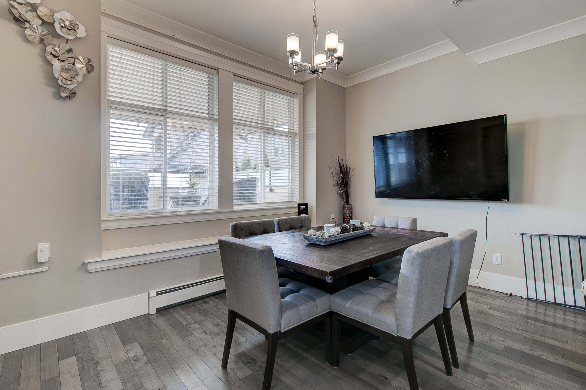 Contemporary dining room in a Vancouver-area home showcased by Orca Realty Inc., featuring modern decor, large windows with natural light, and a sleek flat-screen TV for an inviting living space.