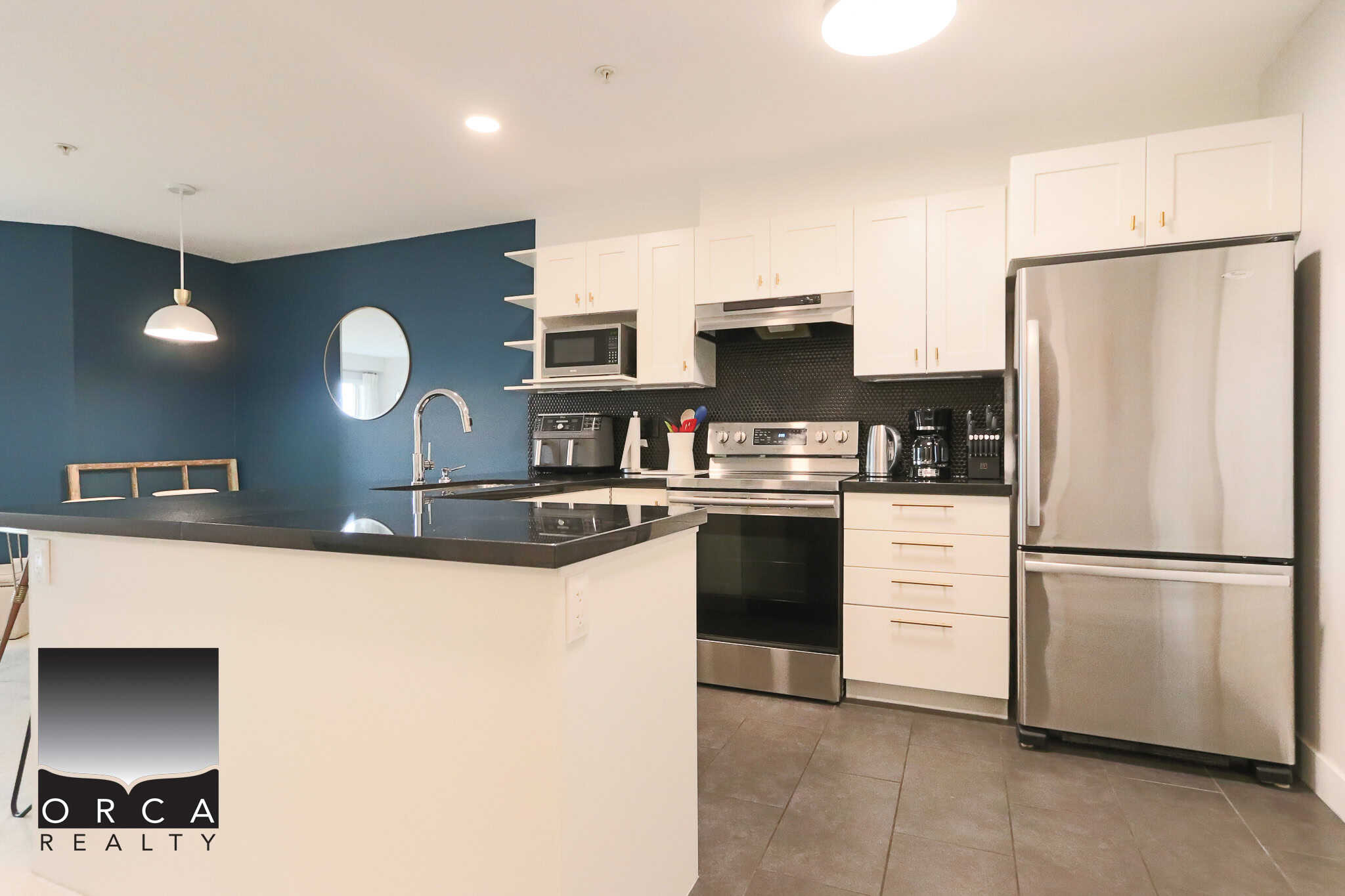 Modern Vancouver-style kitchen with stainless steel appliances, white cabinetry, black backsplash, and spacious island, ideal for Ottawa real estate listings.