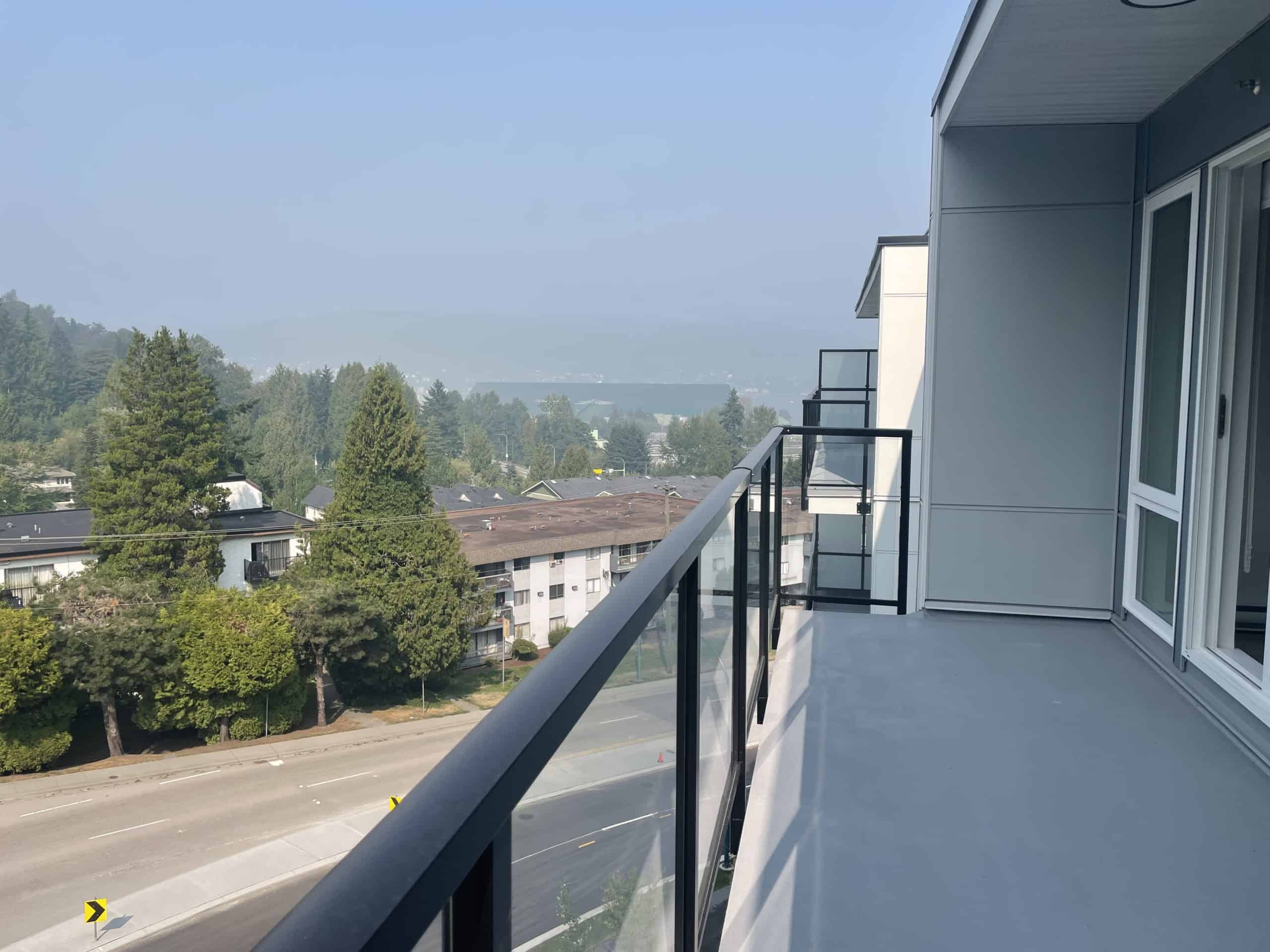 Spacious balcony view of a residential neighborhood with scenic greenery and trees in the background, ideal for enjoying outdoor living in Vancouver, BC.