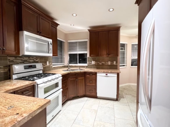 Modern kitchen with dark wood cabinetry, stainless steel appliances, granite countertops, and large tiled flooring, perfect for Vancouver Island real estate buyers.