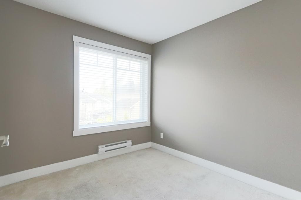 Bright empty bedroom with large window and neutral paint colours, ideal for home buyers and real estate listings in Vancouver.