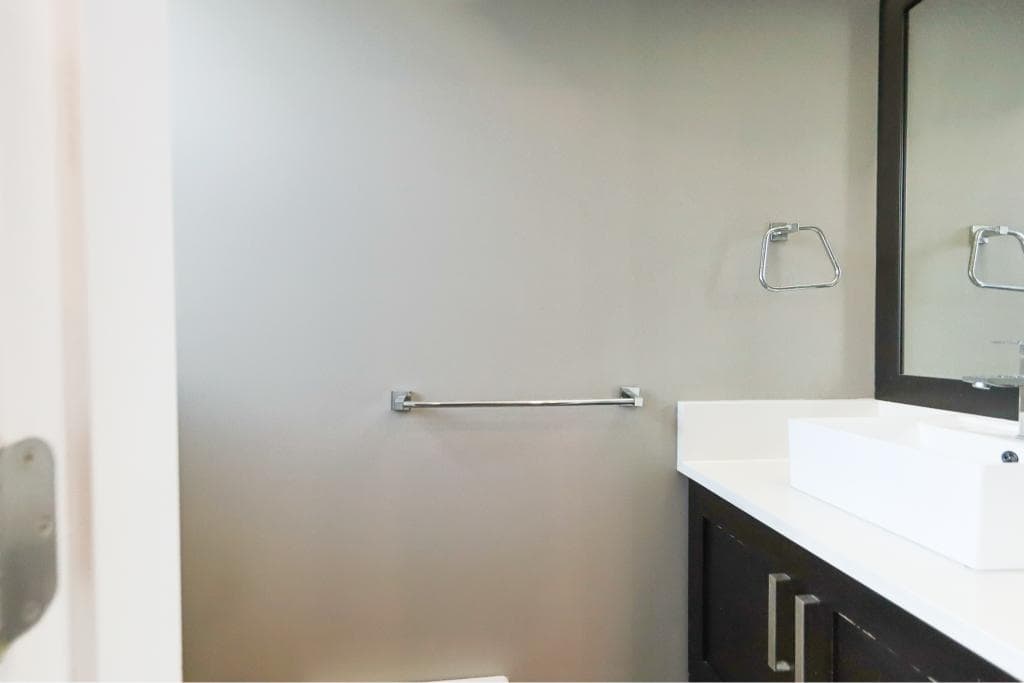 Modern bathroom vanity with a white sink, black cabinetry, and a large mirror, perfect for Vancouver real estate listings and property sales.