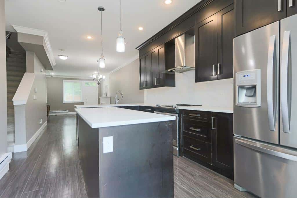 Modern kitchen with black cabinetry and stainless steel appliances in a contemporary home, perfect for living and entertaining in Vancouver.