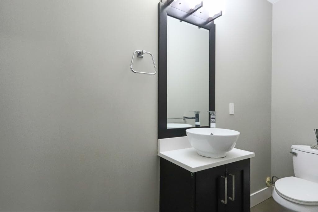 Modern bathroom vanity with vessel sink, sleek mirror, and minimalist decor, ideal for contemporary homes in Victoria, BC. Perfect for buyers seeking stylish and functional home features.