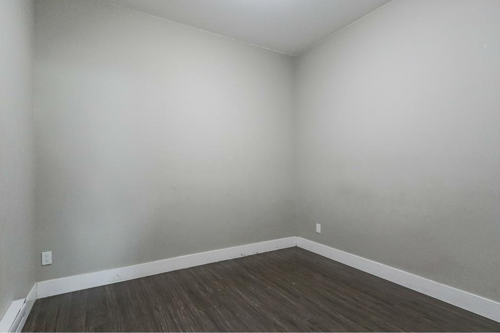 Empty room with white walls and dark wood flooring in a modern property listed by Orca Realty Inc.