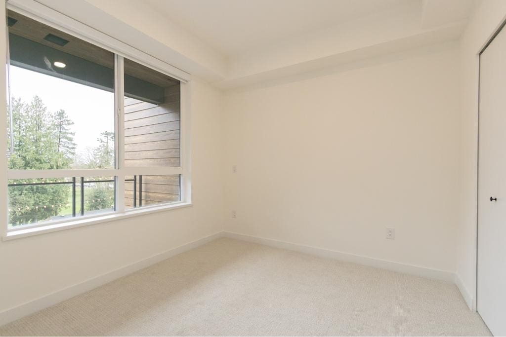 Bright empty bedroom with large window, white walls, and closet space, ideal for Vancouver Island real estate buyers, featured by Orca Realty Inc.