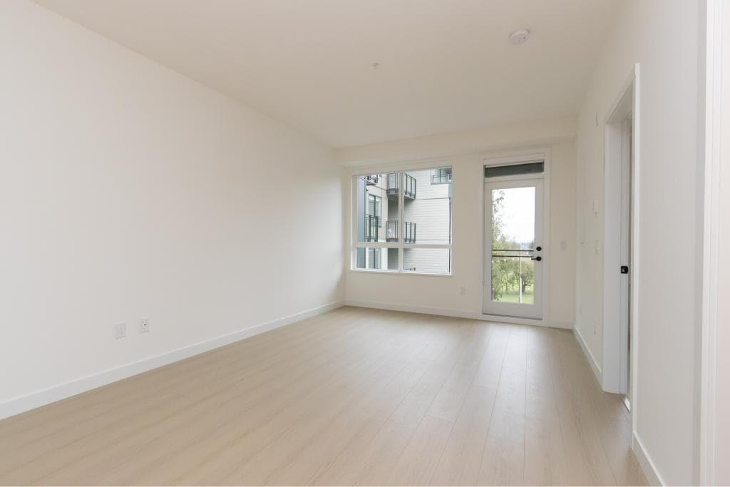 Bright and spacious modern apartment interior with large windows, light wood flooring, and a private balcony, perfect for Vancouver real estate buyers seeking comfortable living spaces.