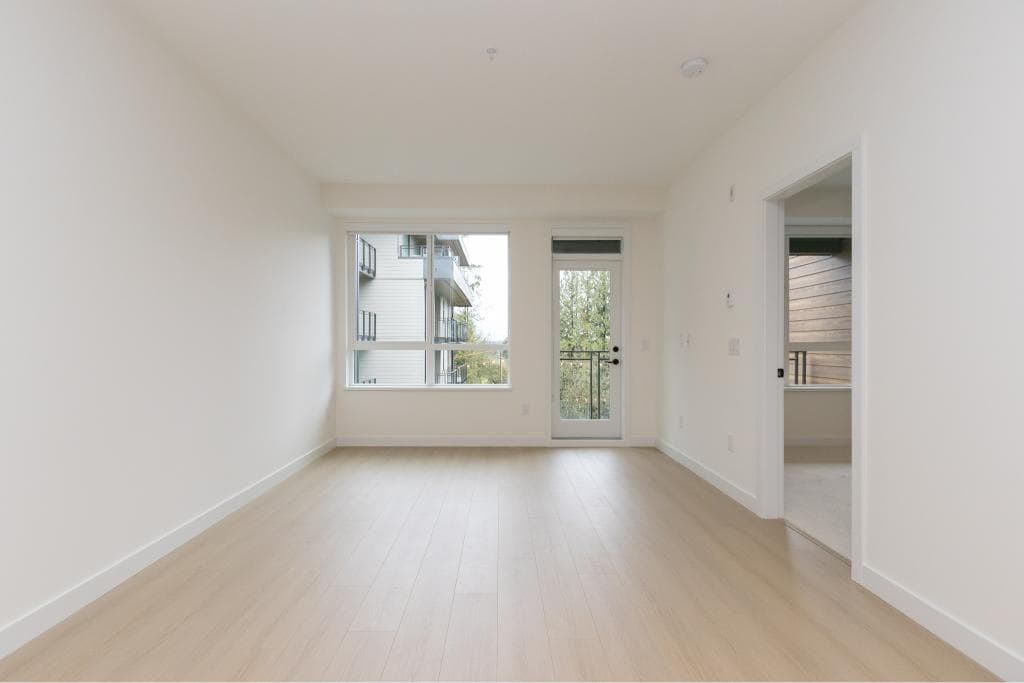 Bright and modern living room in a new Vancouver home with large windows and balcony access, ideal for contemporary living and real estate investment.