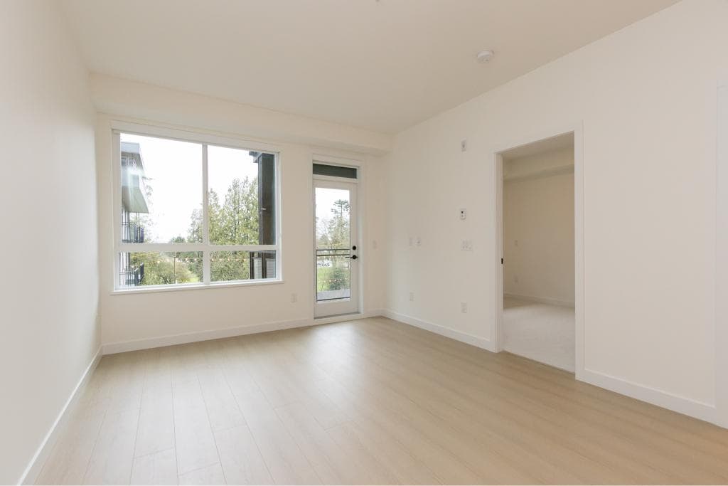 Bright modern living room with large window and natural light, featuring neutral-toned walls and flooring, perfect for homebuyers seeking contemporary real estate options in Vancouver.