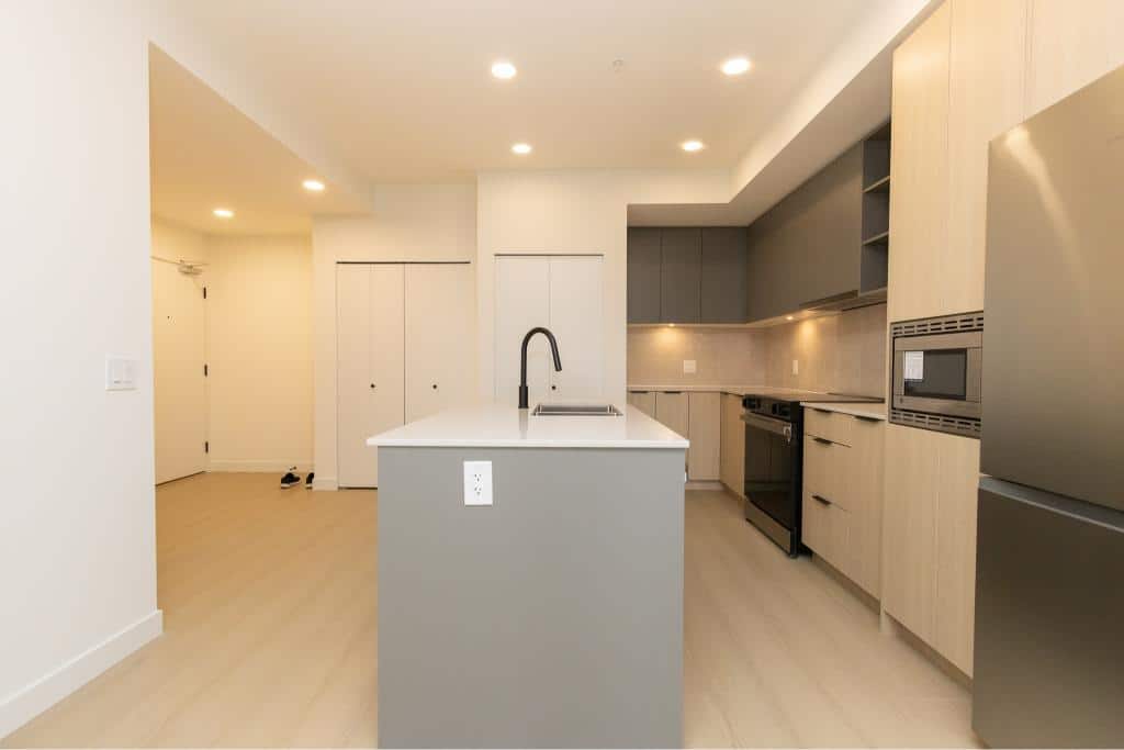 Modern open-concept kitchen with sleek grey and light wood cabinetry, stainless steel appliances, and a central island perfect for living in Vancouver, BC.