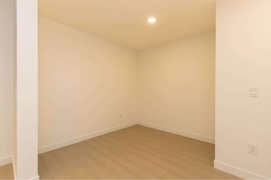 Bright empty room with neutral walls and laminate flooring, ideal for Vancouver real estate and property investment, showcasing modern interiors by Orca Realty Inc.
