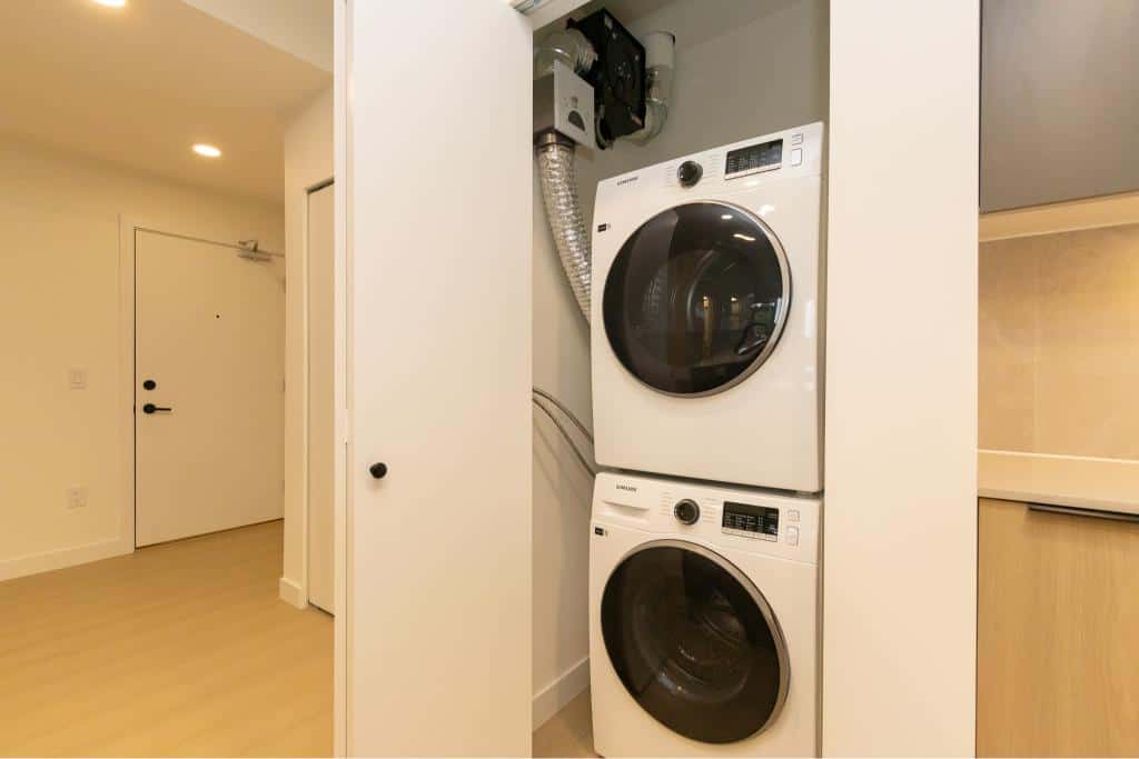 Stacked washer and dryer in a modern apartment laundry area in Victoria, BC, featuring high-efficiency appliances, ideal for urban living, with a sleek design and ample space for convenient laundry chores.