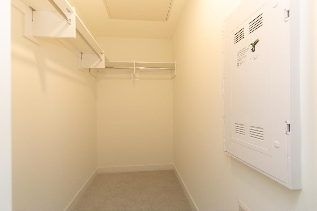 Spacious empty walk-in closet with white built-in shelves and hanging rods, ideal for organized storage in a modern home or apartment in Canada.