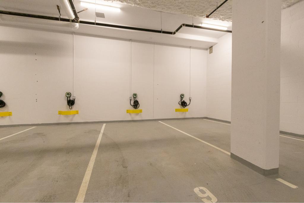 Electric vehicle charging stations in a modern underground parking garage at Orca Realty Inc.