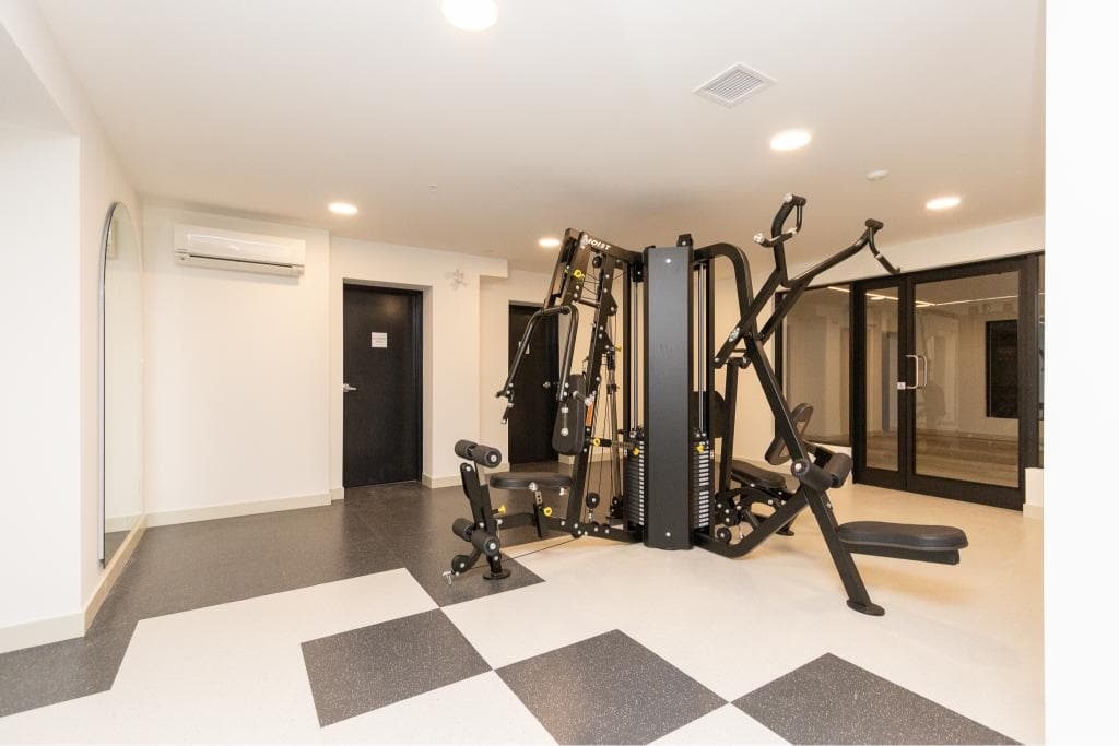 High-end home gym with modern workout equipment in a bright, spacious basement featuring black and white flooring, glass doors, and climate control at Orca Realty Inc.