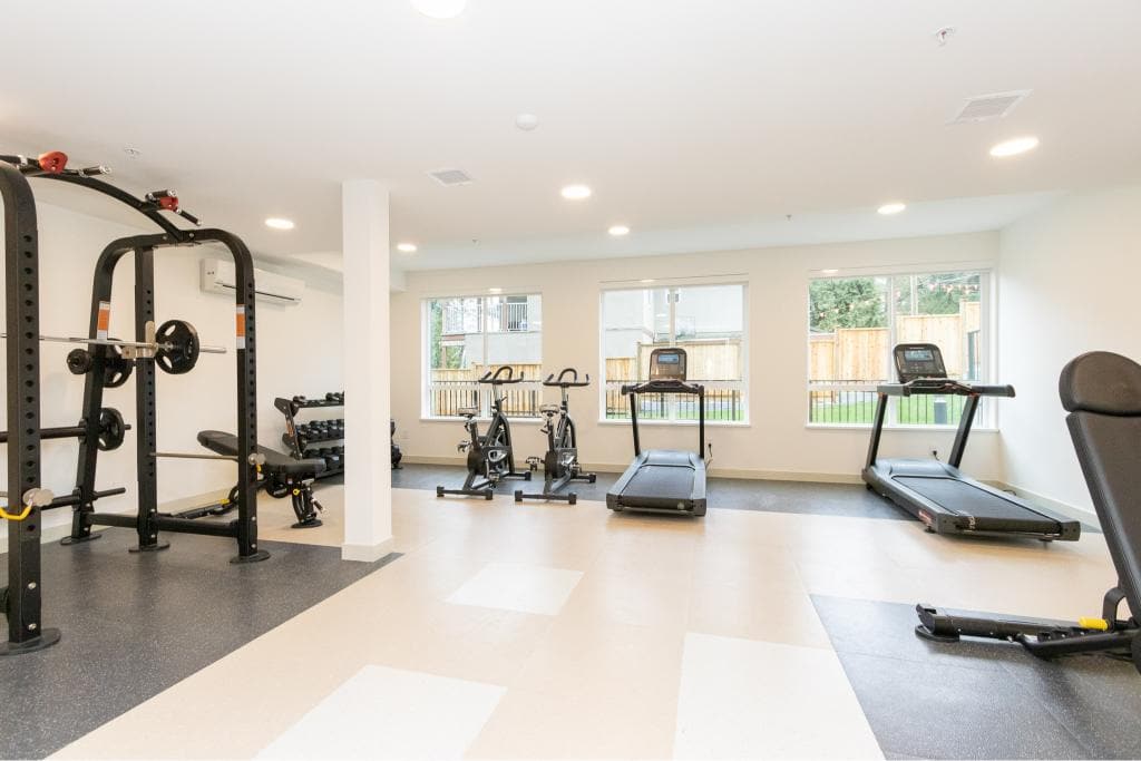 Clean modern indoor fitness room at Orca Realty Inc., featuring cardio equipment and weight training options, ideal for residential or commercial property amenities in BC.