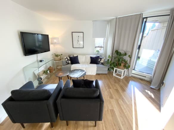 Modern Vancouver condo living room with comfortable seating, large window, and balcony access, perfect for relaxing or entertaining. Well-lit space with stylish decor and hardwood floors.