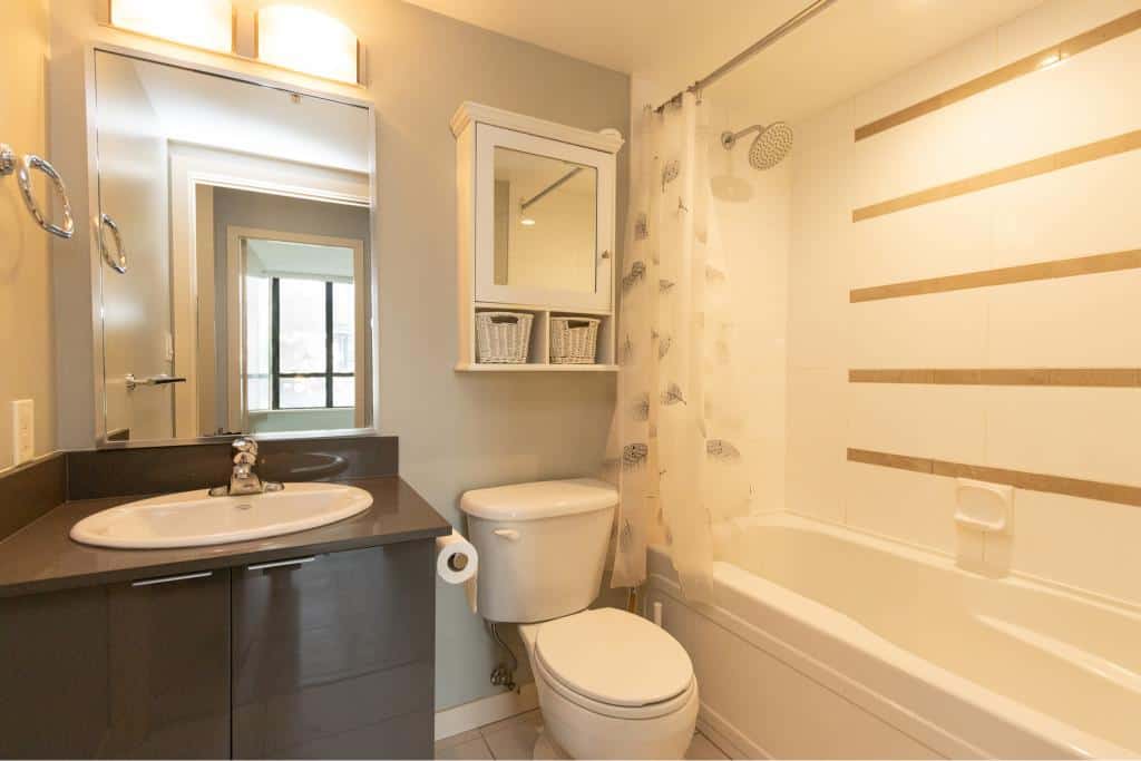 Modern bathroom with vanity, toilet, bathtub, and shower; featuring light blue walls and natural light, perfect for Vancouver real estate listings.