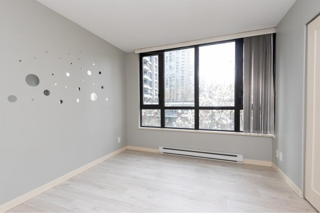 Modern Vancouver apartment interior with large window showcasing city view, ideal for real estate listings and property marketing by Orca Realty Inc.