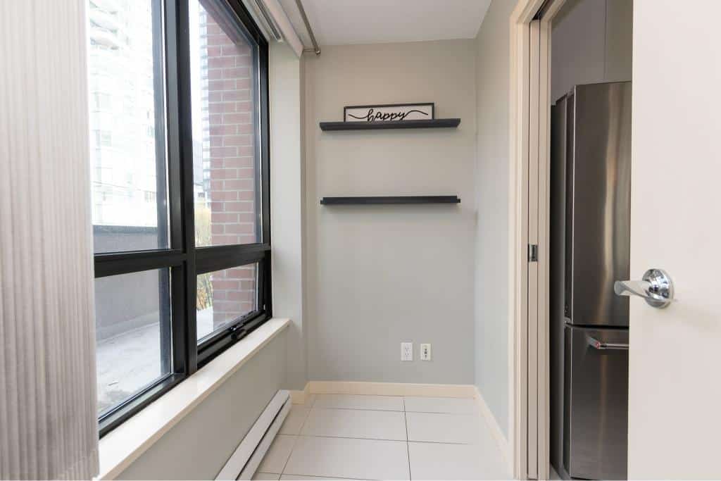 Bright modern kitchen with large window, stainless steel refrigerator, and minimalist decor, ideal for Vancouver property rentals and sales.