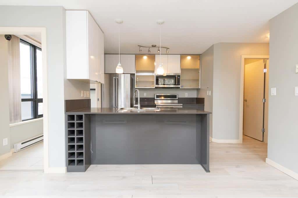 Contemporary modern kitchen with stainless steel appliances, grey and white cabinetry, and a functional island in a stylish apartment. Perfect for urban living and investment opportunities.