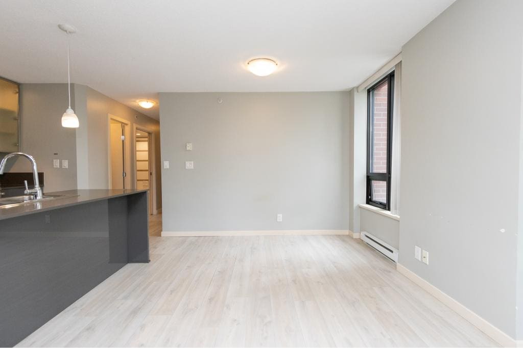 Bright modern open-concept apartment interior with large windows, light wood flooring, and a sleek kitchen featuring a breakfast bar, ideal for Vancouver real estate listings.