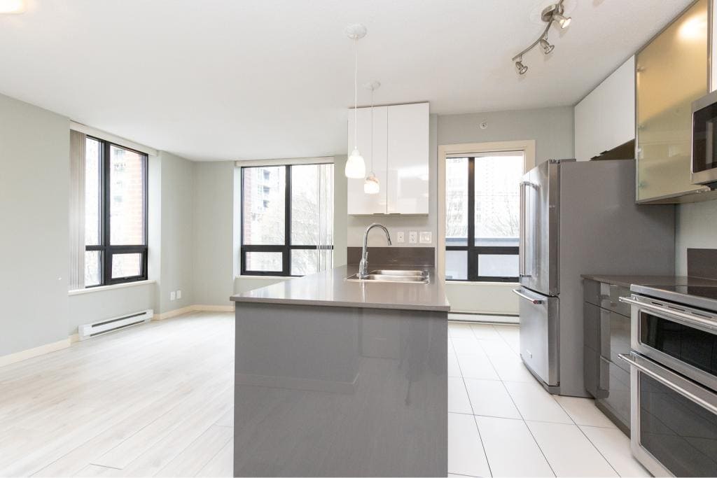 Spacious modern apartment interior with open-plan living area and kitchen, featuring large windows, neutral decor, and updated appliances, ideal for comfortable urban living in Vancouver.