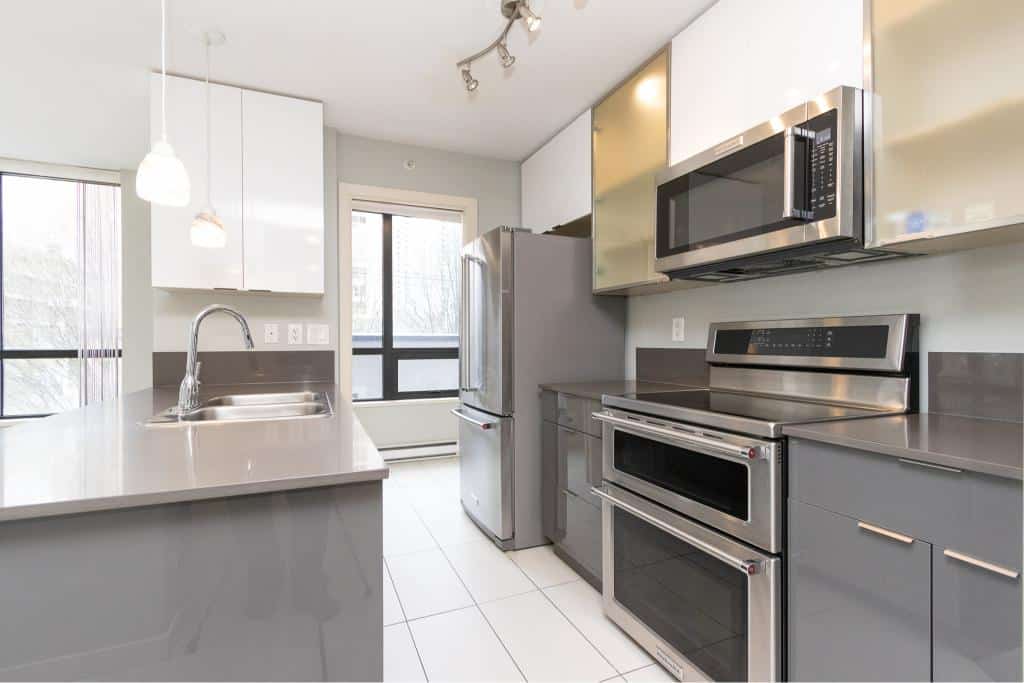 Modern kitchen with stainless steel appliances and grey cabinetry at Orca Realty Inc.