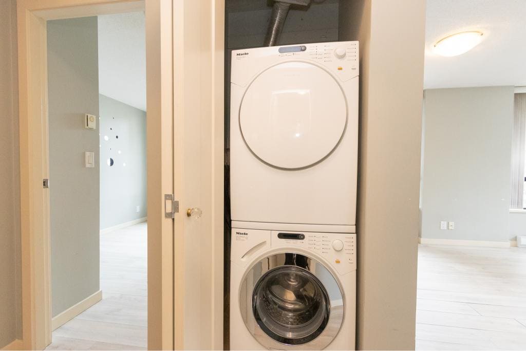 Stacked washer and dryer in a laundry closet, part of a modern home interior in Vancouver, British Columbia, with light-colored walls and flooring.