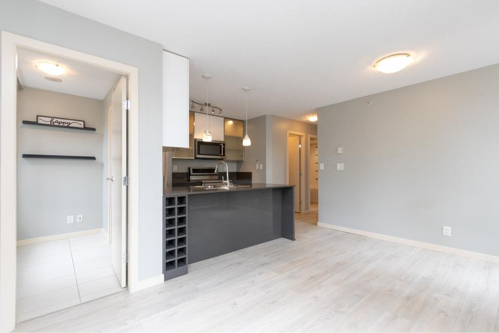 Modern open-concept kitchen in a condo, featuring sleek grey cabinets, a compact wine rack, and contemporary pendant lighting, ideal for Vancouver real estate listings.