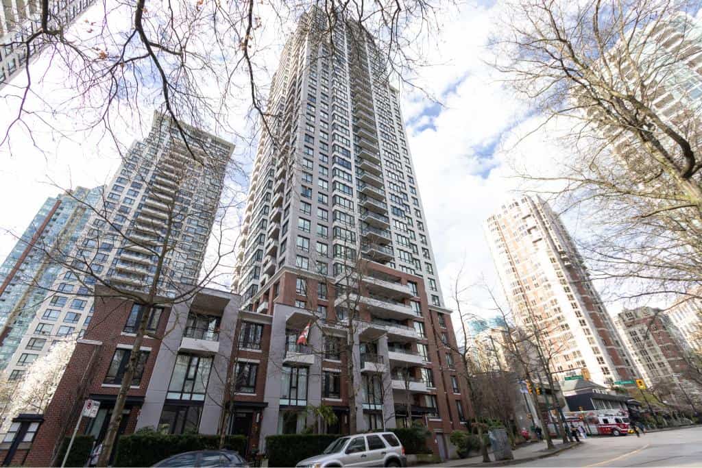 Modern high-rise residential building in downtown Vancouver, BC, featuring luxurious condos, outdoor balconies, and city skyline views, perfect for real estate investment and urban living.