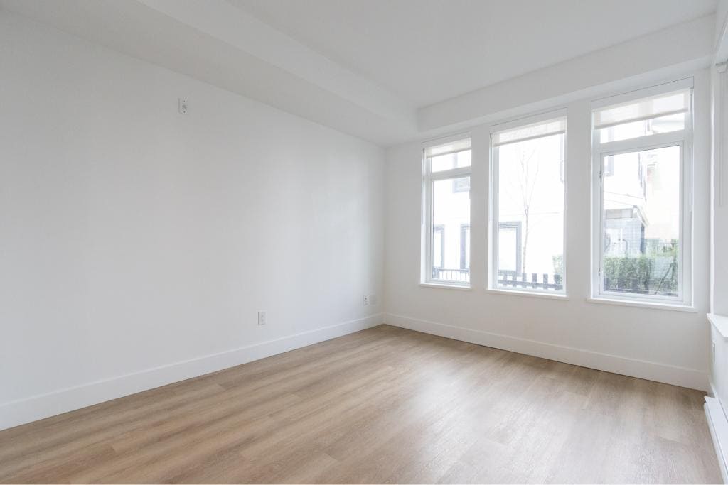 Bright renovated living room with large windows, natural light, and hardwood flooring, perfect for Vancouver homebuyers seeking modern city living.