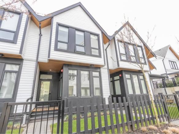 Modern Vancouver-style townhouse with white and black exterior, large windows, and private front yard in a family-friendly neighbourhood.
