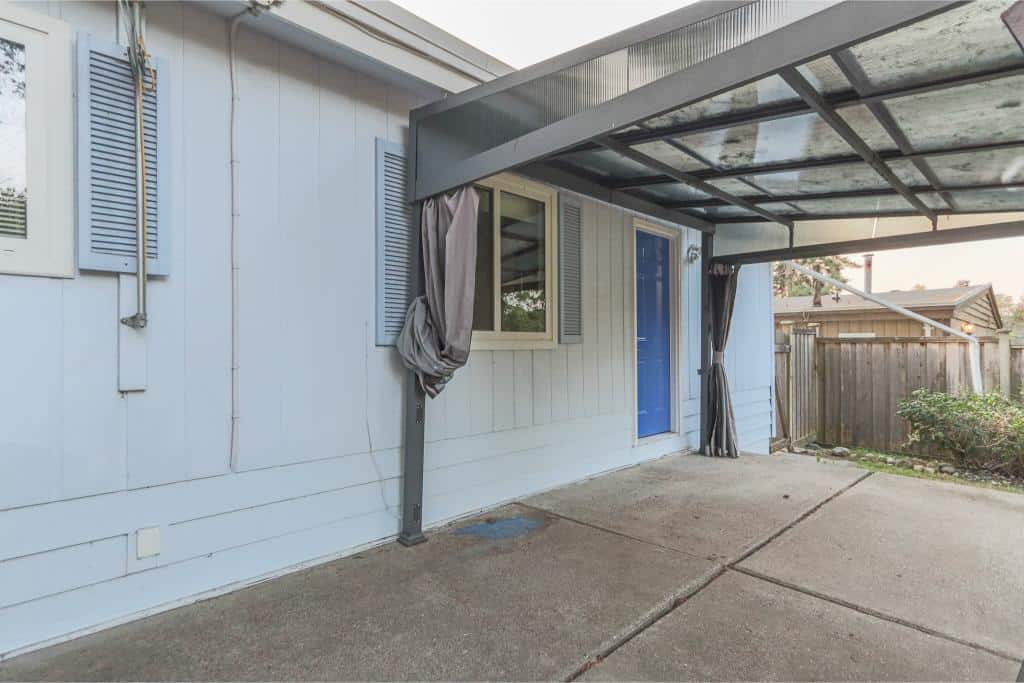 Modern outdoor patio area with covered space, white siding, and blue door, ideal for relaxing or entertaining in Vancouver's real estate market.