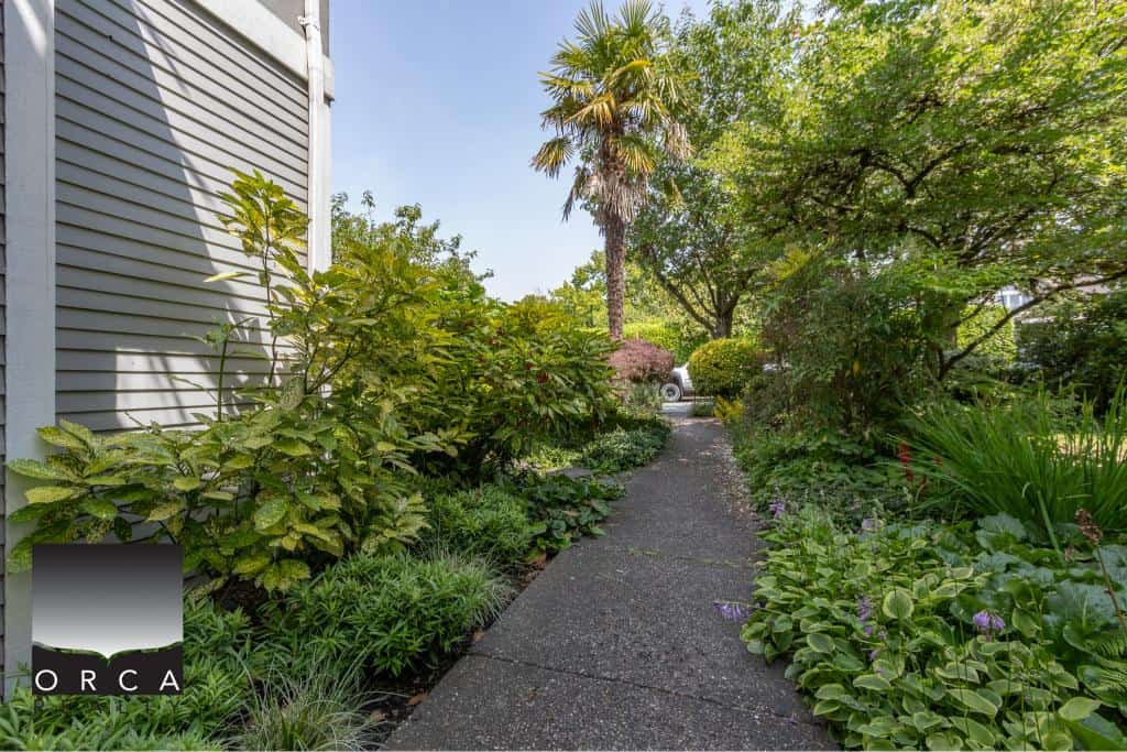 Lush garden pathway leading to a residential home in Victoria, BC, showcasing beautiful landscaping and greenery.