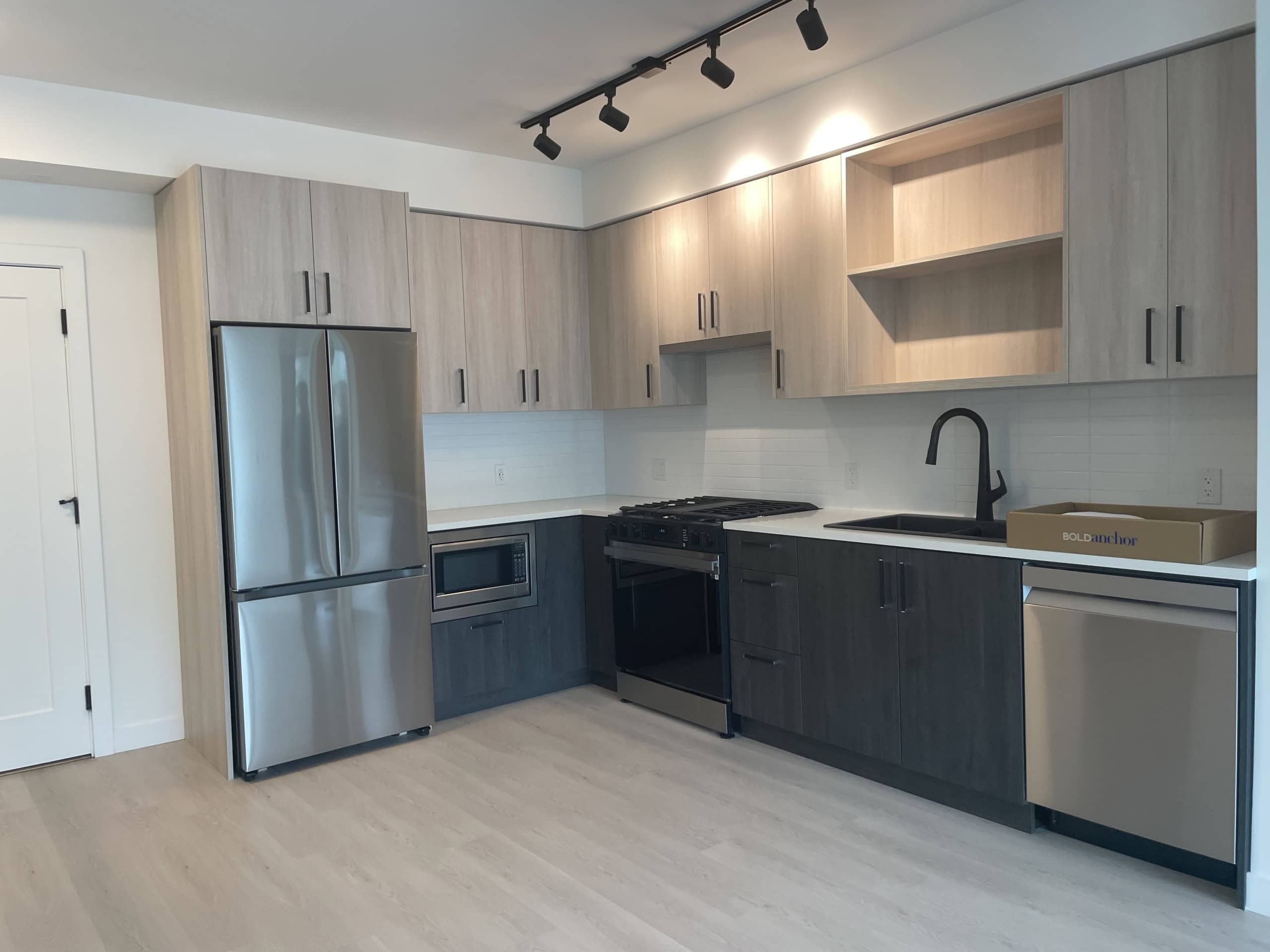 Bright modern kitchen with light wood and dark grey cabinetry, stainless steel appliances, and minimalist design, perfect for contemporary Vancouver homes.