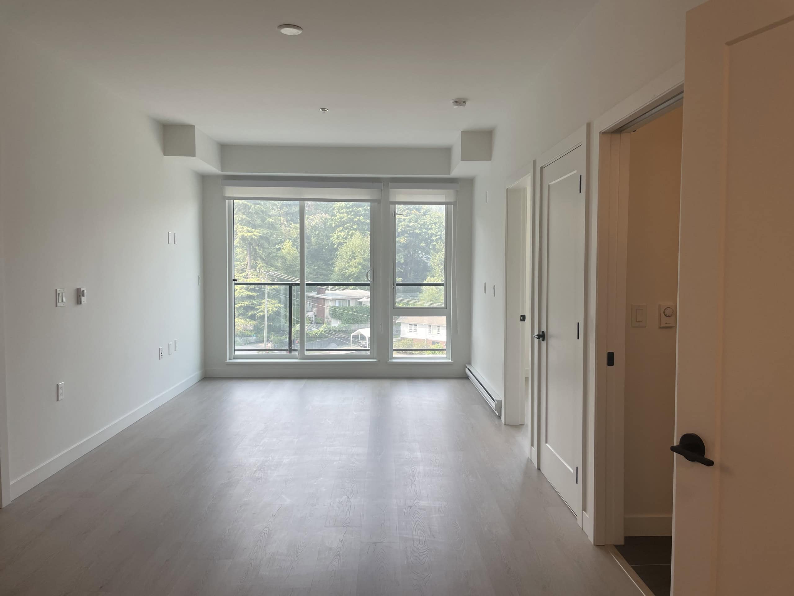 Bright, modern living room with large floor-to-ceiling windows showcasing a scenic view, ideal for Vancouver Island real estate and condo listings in BC.
