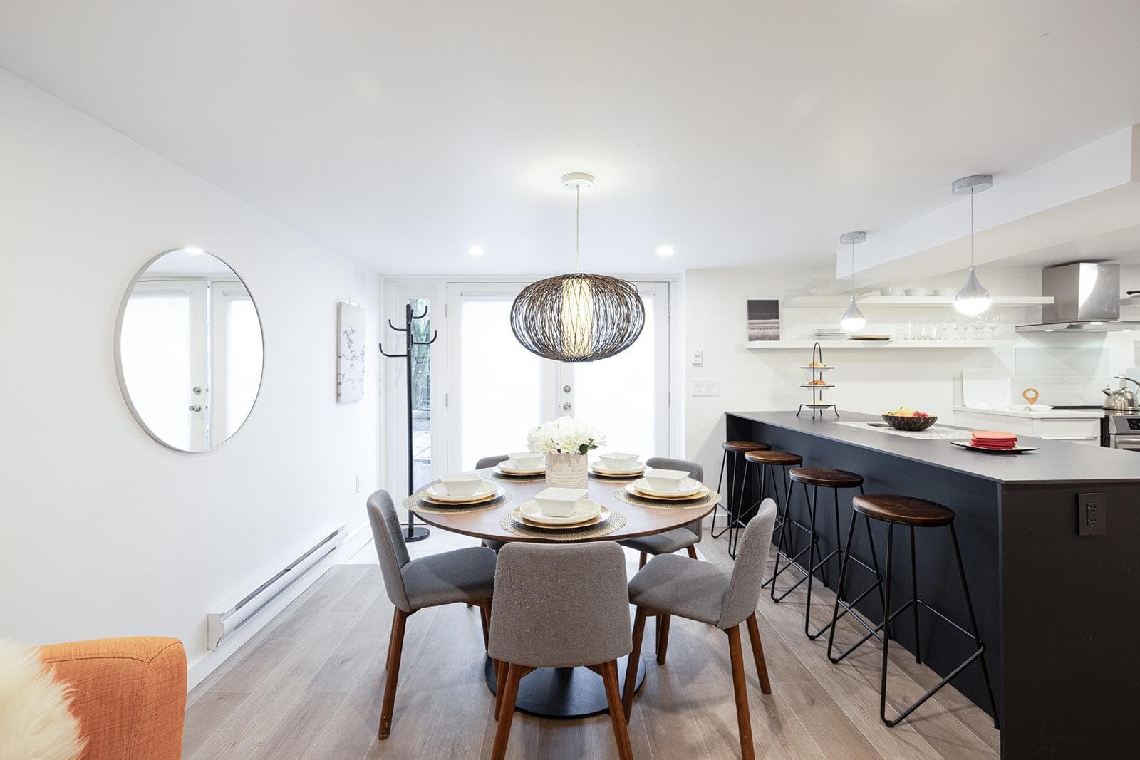 Modern open-concept dining and kitchen area in a contemporary Ottawa home, showcasing stylish furniture, breakfast bar with stools, and sleek design with natural lighting.