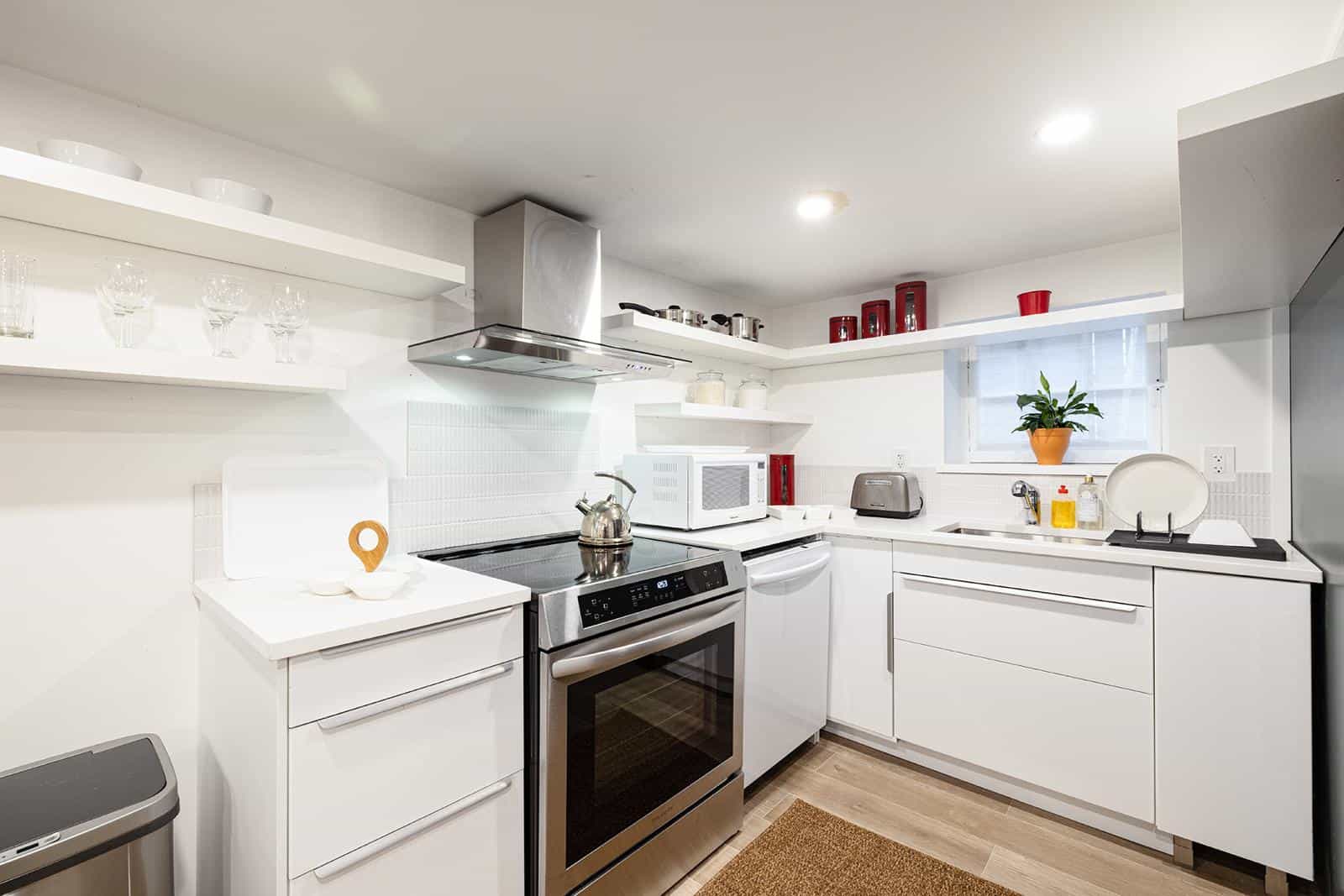 Bright, modern white kitchen with stainless steel appliances, open shelving, and natural light, perfect for Vancouver real estate listings and showcasing homes in the Orca Realty Inc. portfolio.