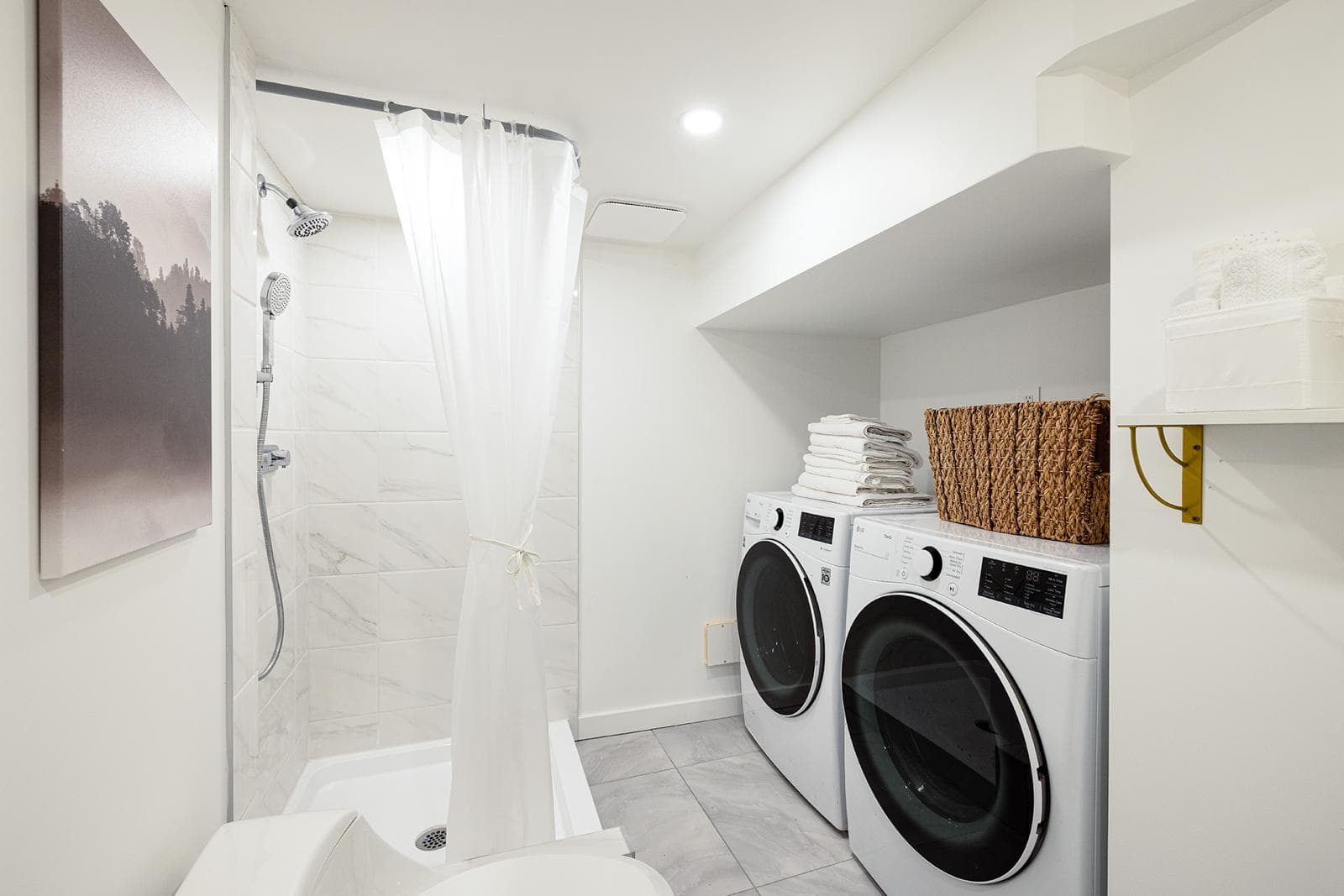 Modern laundry room with washer and dryer, white walls, and a walk-in shower with a curtain, ideal for Vancouver home buyers seeking functional and stylish utility spaces.