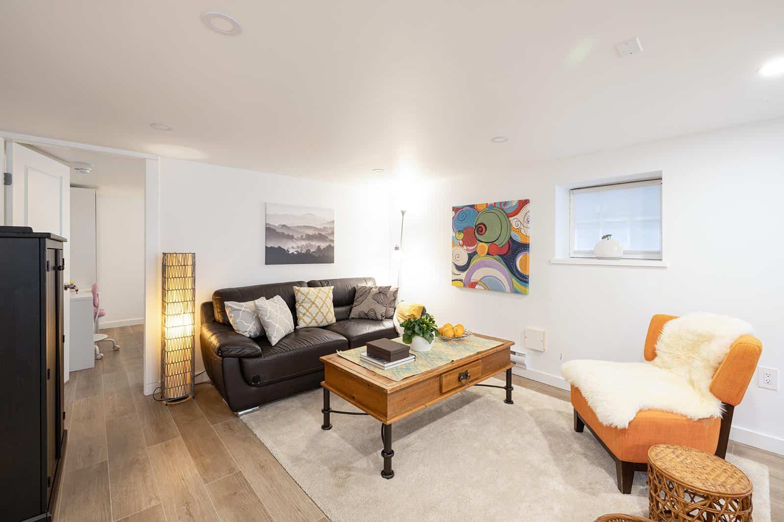 Cozy living room with modern decor, featuring a leather sofa, colorful artwork, and stylish furniture in a Vancouver area home, showcasing Orca Realty Inc. property listings.